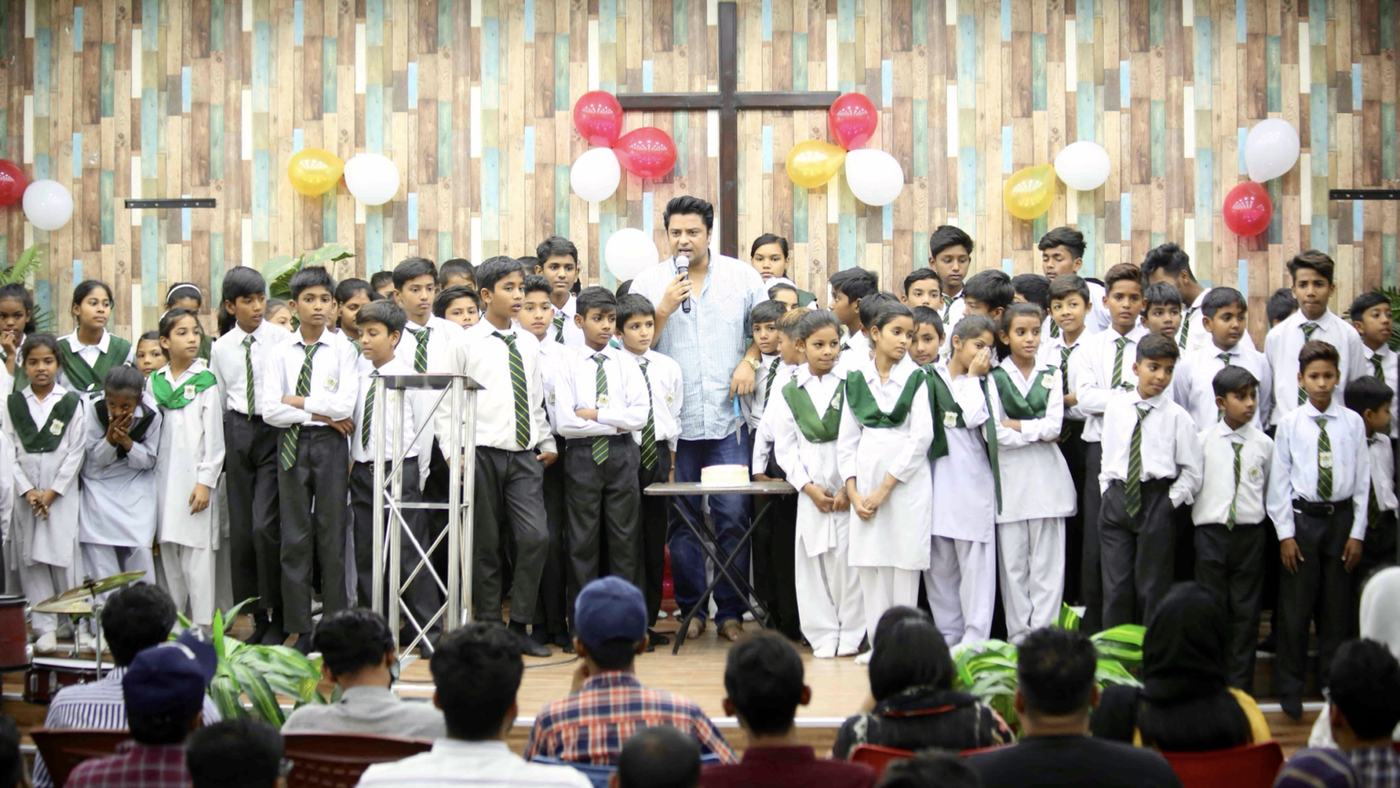 Pupils singing on stage in front of the cross